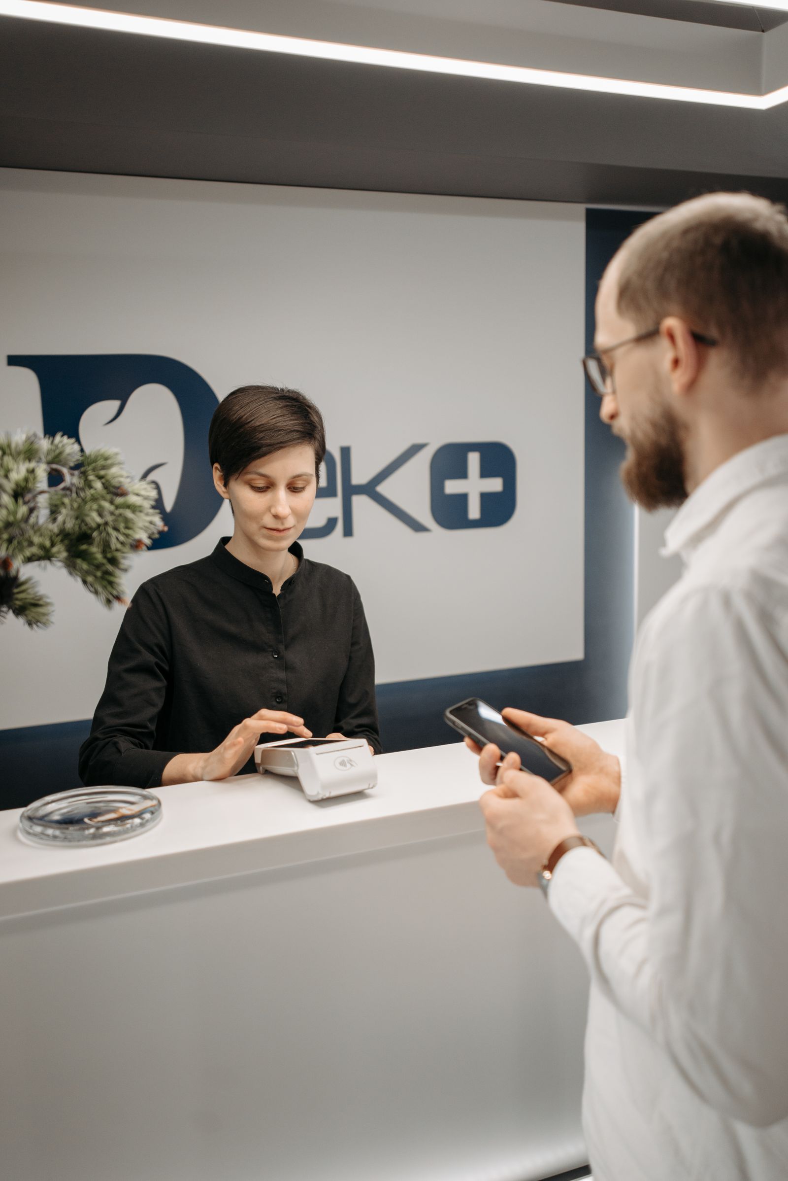 Patient zahlt kontaktlos am Empfang einer modernen Praxis