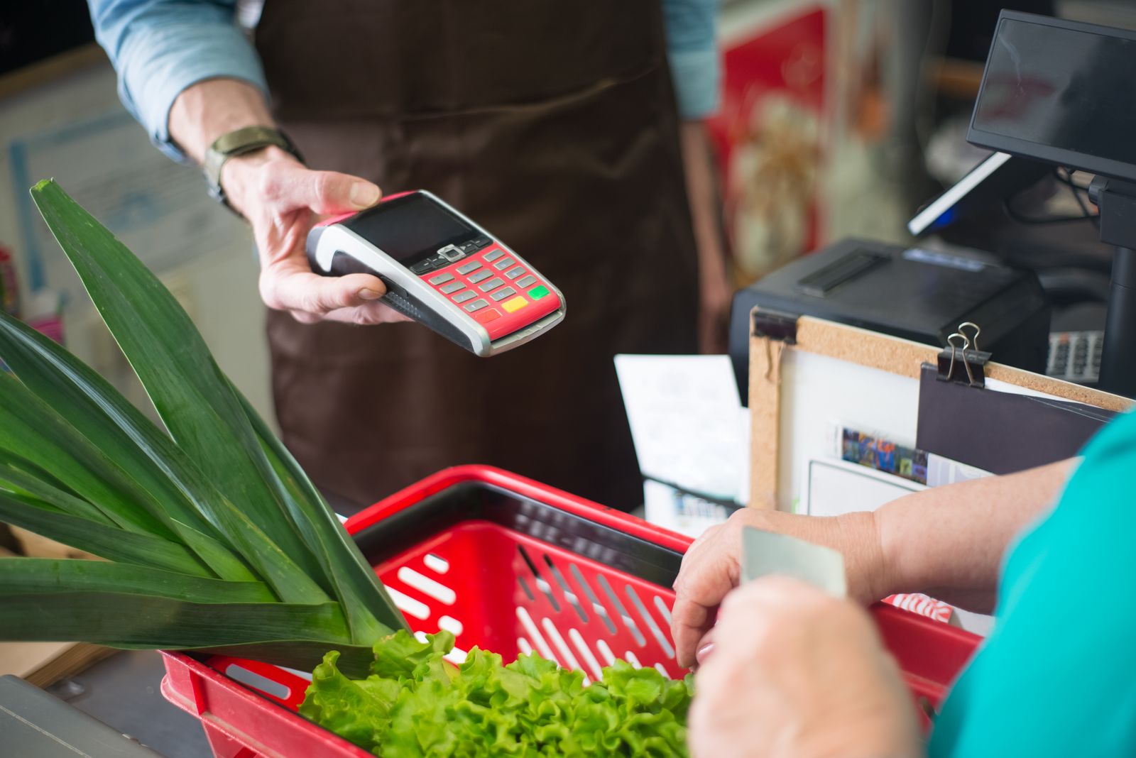 Kassierer reicht das Kartenterminal an der Supermarktkasse